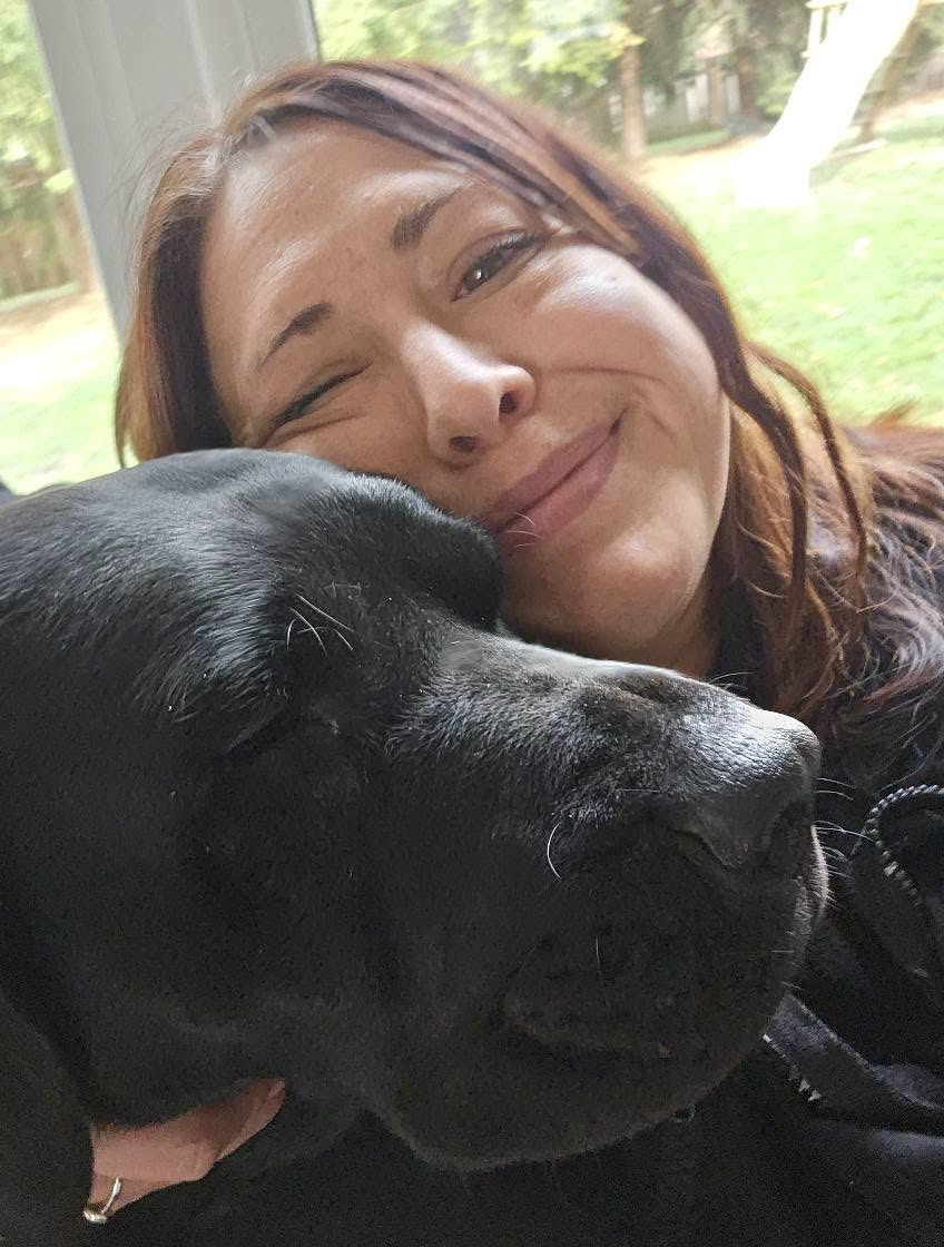 Julie cheek to cheek with a black lab