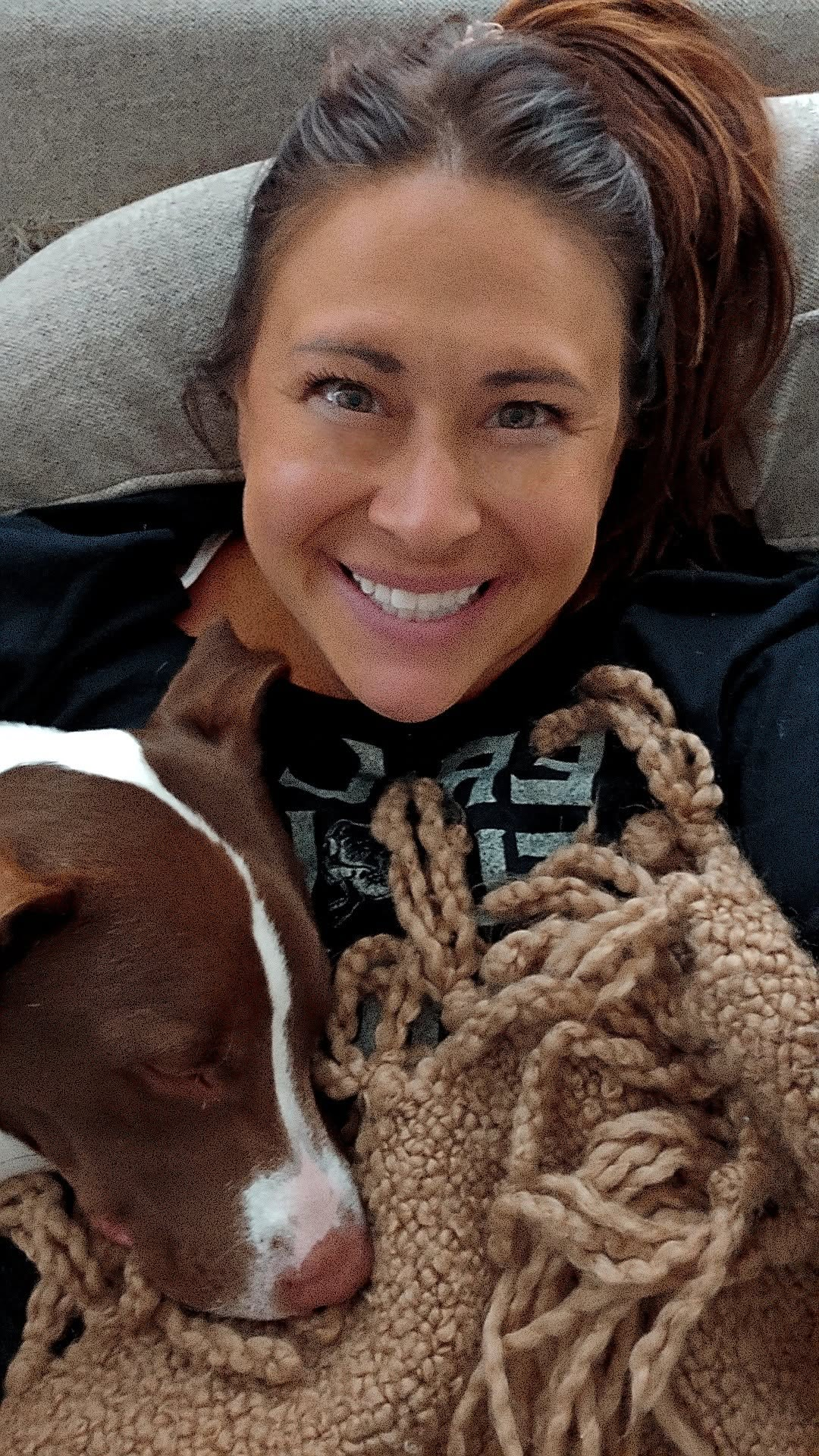 Julie with a dog snuggled under a cozy blanket